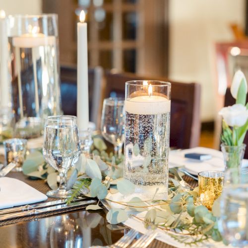 A beautifully set dining table with candles, glassware, napkins, and floral arrangements, creating an elegant and inviting atmosphere.
