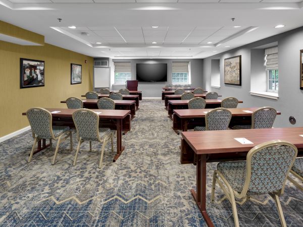 A conference room with rows of desks and chairs facing a large screen, suitable for meetings or presentations.